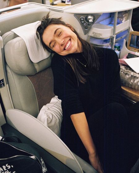 Alexis Ren in a black dress poses in her car.